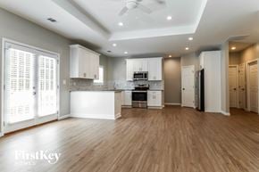 Dacula house for rent - A spacious kitchen with wooden floors and white cabinetry.