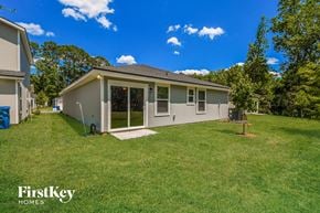Jacksonville house for rent - a gray house with a grassy yard and trees
