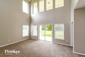 Orange Park house for rent - an empty living room with windows and a door to a yard