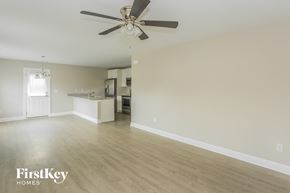 Kannapolis house for rent - an empty living room with a ceiling fan and a kitchen