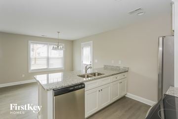 Kannapolis house for rent - a kitchen with white cabinets and granite counter tops and a stainless steel refrigerator