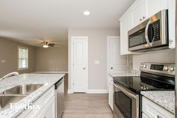 Kannapolis house for rent - a kitchen with white cabinets and black appliances and a sink