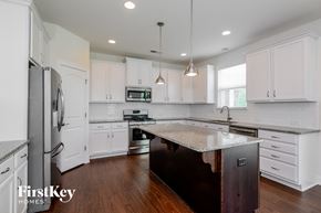 Belmont house for rent - a kitchen with white cabinets and a marble counter top