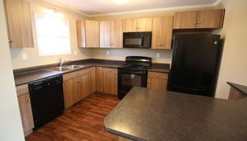 Saskatoon apartment for rent - A kitchen with black appliances and wooden cabinets.