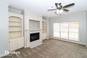 Collierville house for rent - a living room with a fireplace and shelves and a ceiling fan