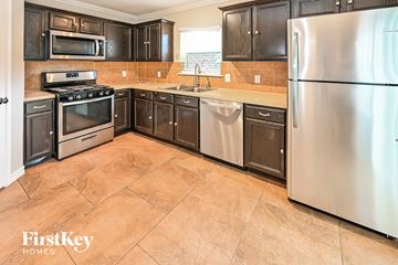 Baytown house for rent - a kitchen with stainless steel appliances and wooden cabinets