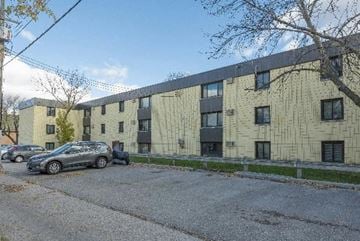 Winnipeg apartment for rent - a large building with cars parked in front of it