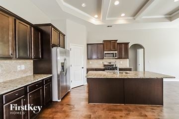 Mcdonough house for rent - A kitchen with dark brown cabinets and a granite countertop.