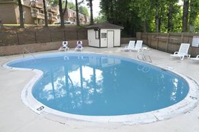 Collinsville apartment for rent - A small pool with a white fence and a brown building in the background.