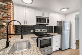 Denver apartment for rent - A kitchen with a brick wall and a stainless steel refrigerator.