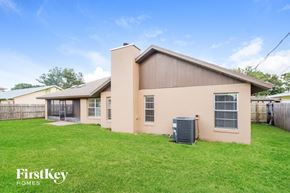 Palm Bay house for rent - a beige house with a yard and a heater in the grass
