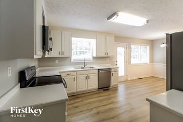 Loganville house for rent - a kitchen with white cabinets and a sink and a refrigerator