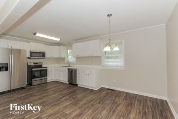 Gastonia house for rent - a kitchen with white cabinets and stainless steel appliances
