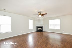 Winston-Salem house for rent - an empty living room with a ceiling fan and a fireplace