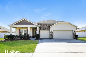 Haines City house for rent - a beige house with a garage door and a lawn