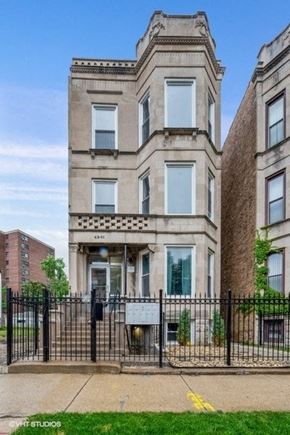 Chicago apartment for rent - A tall building with a black fence in front of it.