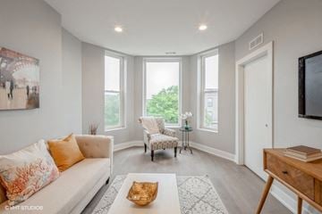 Chicago apartment for rent - A living room with a white sofa and a chair with a floral pattern.