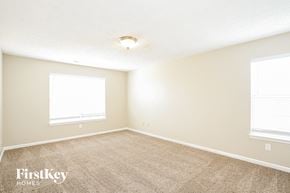 Greenfield house for rent - a spacious room with carpet and two windows