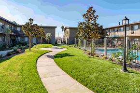 Westminster apartment for rent - a path through the grass between two apartment buildings and a pool