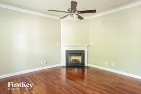 Charlotte house for rent - a living room with wood floors and a fireplace and a ceiling fan