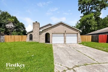 Humble house for rent - a brick house with a white garage door and a lawn