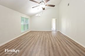 Humble house for rent - an empty living room with wood flooring and a ceiling fan