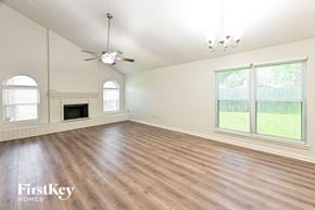 Humble house for rent - an empty living room with wood floors and a fireplace