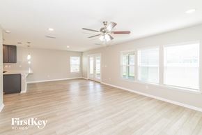 Jacksonville house for rent - an empty living room with a ceiling fan and windows