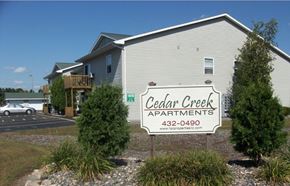 Kronenwetter apartment for rent - A building with a sign that says Cedar Creek Apartments.