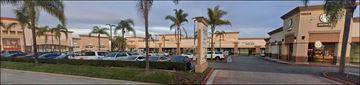 Huntington Beach apartment for rent - A parking lot in front of a shopping center with palm trees.