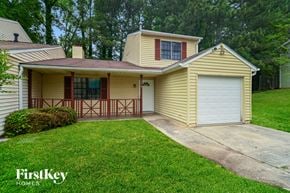 Atlanta house for rent - A yellow house with a garage door and a brown fence.
