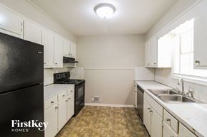 Conyers house for rent - a kitchen with white cabinets and black appliances