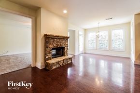 Buford house for rent - an empty living room with a stone fireplace and wooden floors