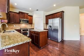 Buford house for rent - a kitchen with wooden cabinets and granite counter tops and a stainless steel refrigerator