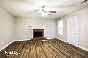 Riverdale house for rent - A room with a fireplace and a ceiling fan.