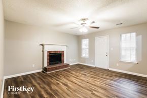 Riverdale house for rent - A spacious room with a fireplace and a ceiling fan.