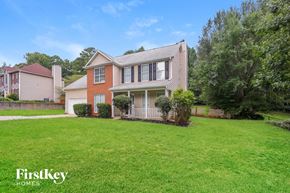 Hampton house for rent - A house with a red roof and a white fence is surrounded by green grass.