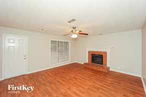 Hampton house for rent - A room with a fireplace and a ceiling fan.