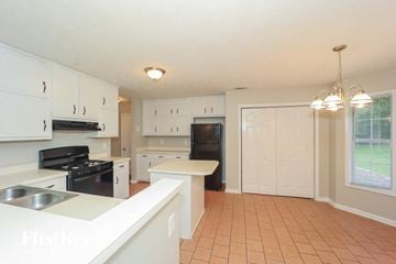 Hampton house for rent - A kitchen with white cabinets and a black stove top oven.
