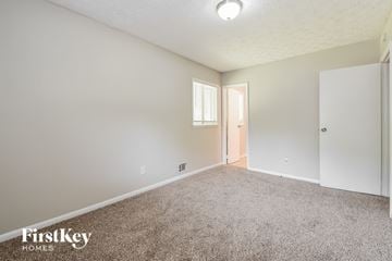 Jonesboro house for rent - a spacious living room with carpet and a door to a bedroom