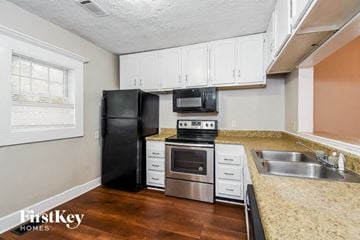 Atlanta house for rent - a kitchen with white cabinets and a black refrigerator