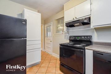 Atlanta house for rent - a kitchen with white cabinets and black appliances and a black refrigerator