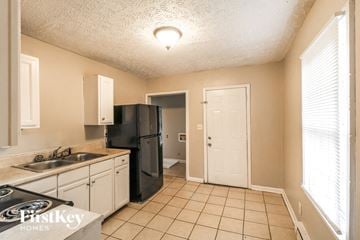 Decatur house for rent - A kitchen with a black fridge and white cabinets.