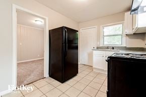 Decatur house for rent - a kitchen with a black refrigerator and white cabinets