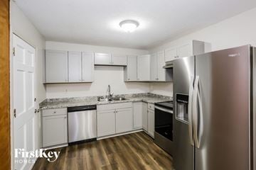 Gastonia house for rent - a kitchen with white cabinets and stainless steel appliances
