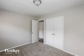 Gastonia house for rent - a bedroom with white closets and carpet and a door to a hallway