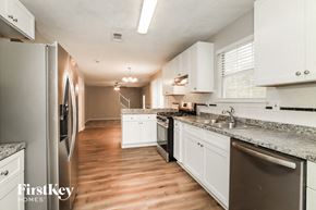 Decatur house for rent - a kitchen with white cabinets and stainless steel appliances and a wood floor