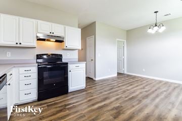 Hampton house for rent - A kitchen with white cabinets and a black stove top oven.