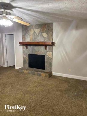 Marietta house for rent - A stone fireplace with a wood mantle is in a room with a carpeted floor.
