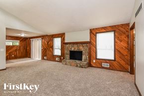 Marietta house for rent - an empty living room with a stone fireplace and wooden walls